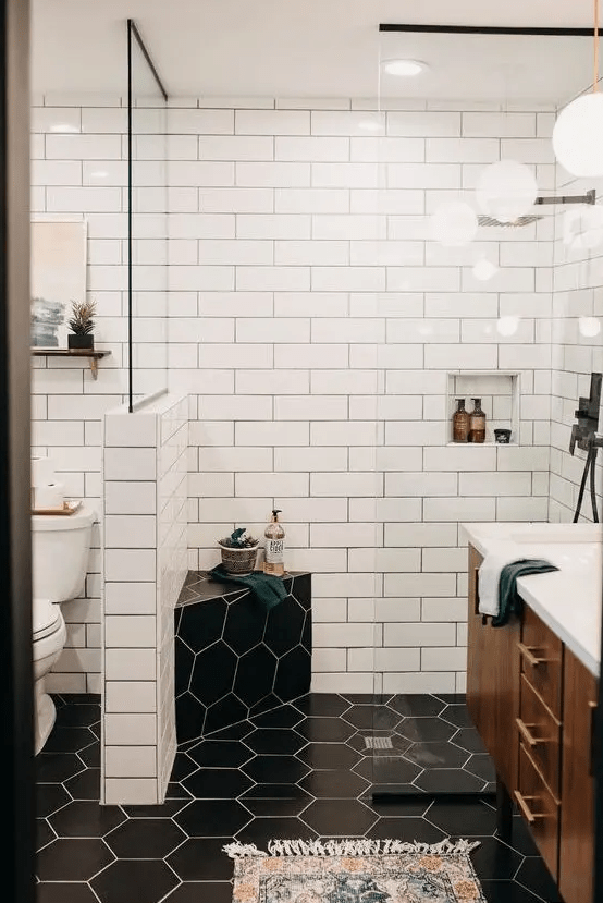 a contrasting mid-century modern bathroom with white subway and black hex tiles, a richly stained vanity and touches of gold