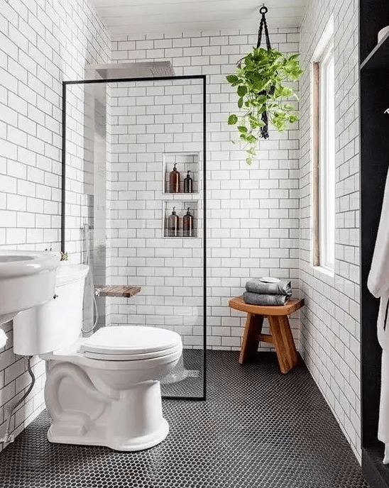 a modern bathroom with penny and subway tiles, built-in shelves, a sink and a wooden stool