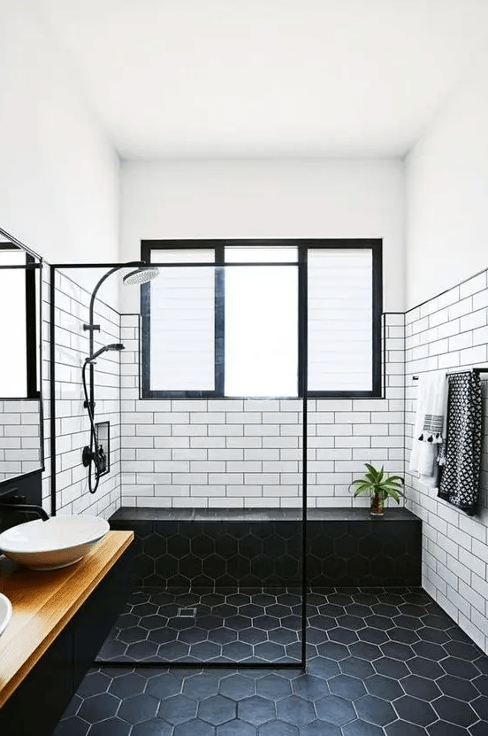 a striking monochromatic bathroom with white subway tiles and black hexagon tiles, a floating vanity and sink, and black fixtures