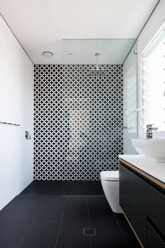 a minimalist bathroom with black tile floors, white walls and a geo accent wall, a black vanity and white appliances