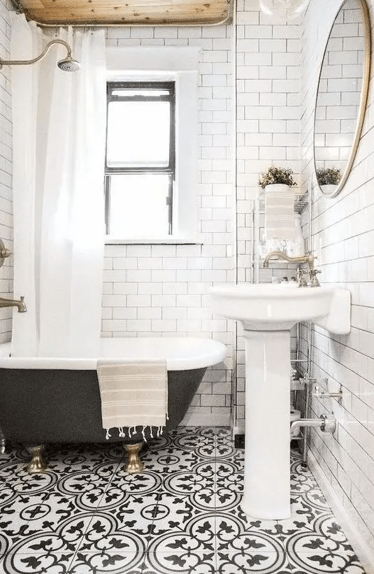 a small and bright bathroom with mosaic floors, a wooden ceiling, a black clawfoot bathtub and a freestanding sink