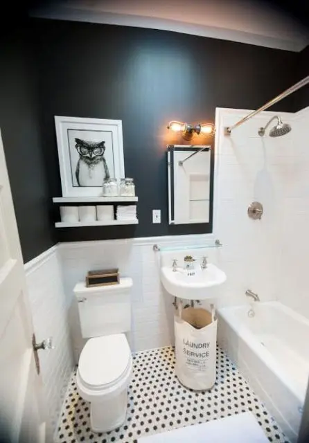a small black and white bathroom with black walls, a white tiled bathtub area, a wall sink and some decor