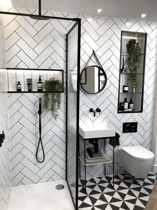 a small modern bathroom with herringbone tiled walls, a printed floor, a small sink and a shower with a glass partition