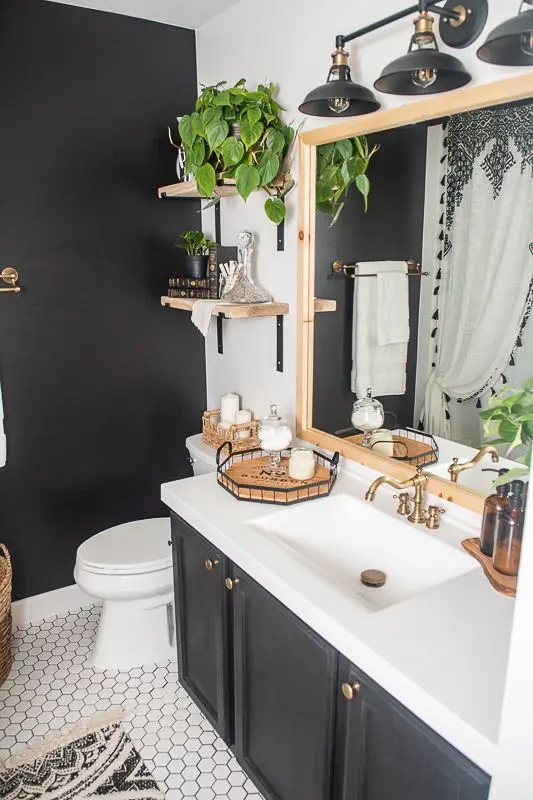 a vintage-style bathroom with a black accent wall and vanity, white appliances, stained shelves and a mirror in a stained frame