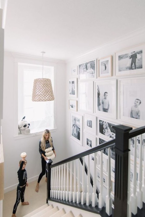 A freely designed gallery wall with black and white family pictures and white frames is a very chic and stylish idea for any room