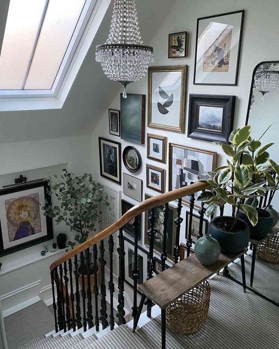 A floor-to-ceiling gallery wall with a stair wall, a crystal chandelier and some greenery on the bench create a wow look