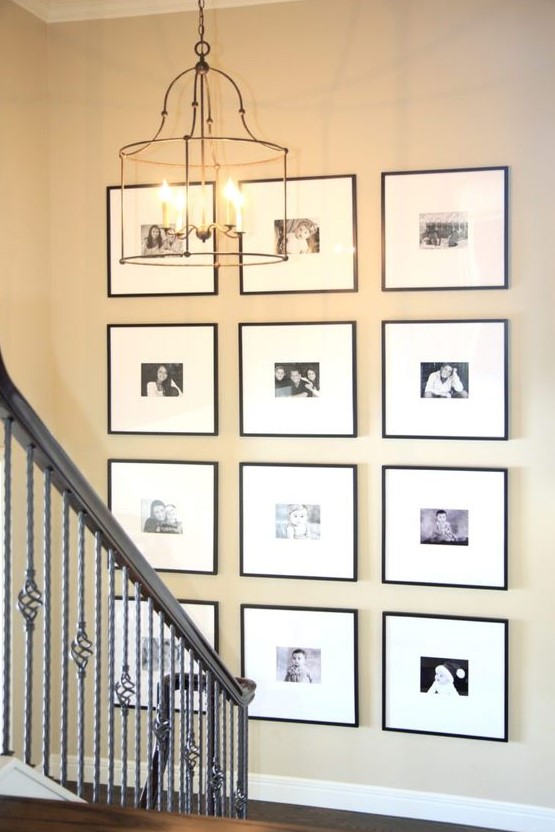 A gallery wall with a grid pattern, family photos, black frames and white mats is a stylish and elegant way to decorate the space