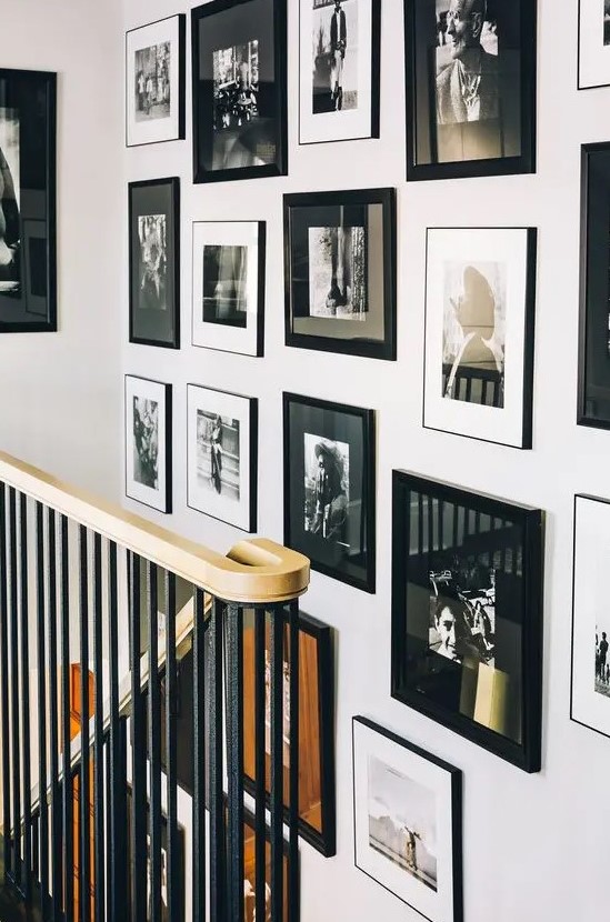 A beautiful freeform gallery wall with mismatched black frames, black and white mats, and chaotically placed artwork