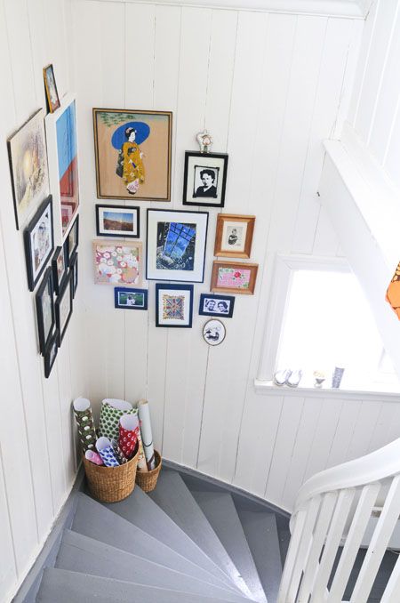 A beautiful and colorful corner gallery wall with mismatched frames is a cool solution for a small staircase