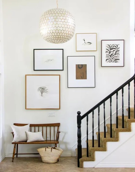 A minimalist staircase gallery wall in black, white and neutral tones with mismatched black and neutral frames