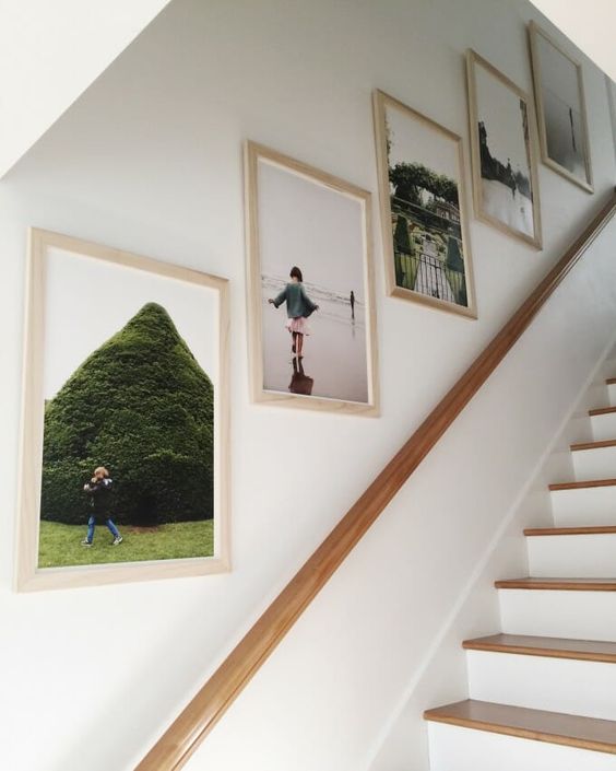 A simple and cool gallery wall with a grid pattern and family photos in bright frames is a cool idea for a modern staircase