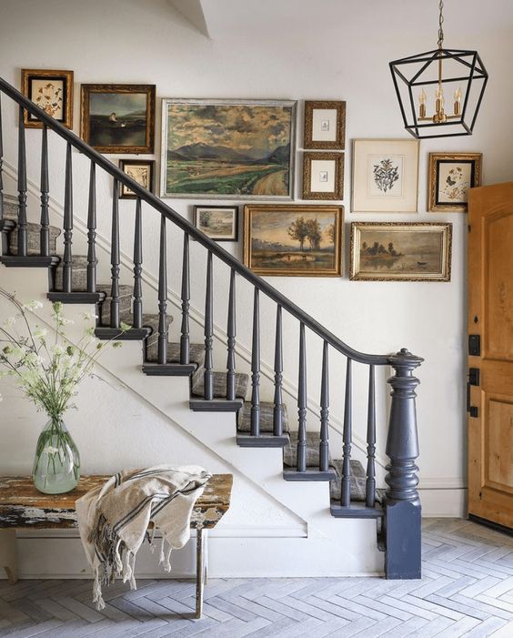 A sophisticated gallery wall of vintage artwork and mismatched frames for a vintage farmhouse entryway