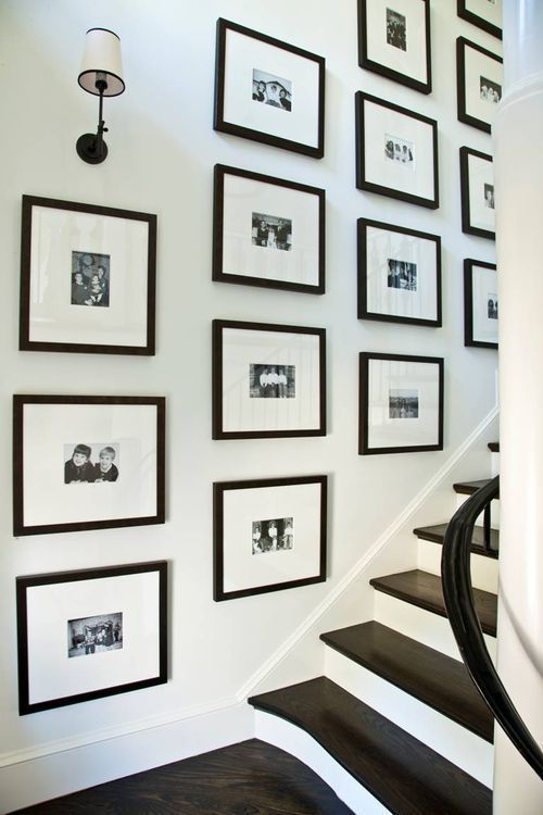A gallery wall with black and white grids and black and white family pictures is a cool and stylish idea that brings ultimate elegance