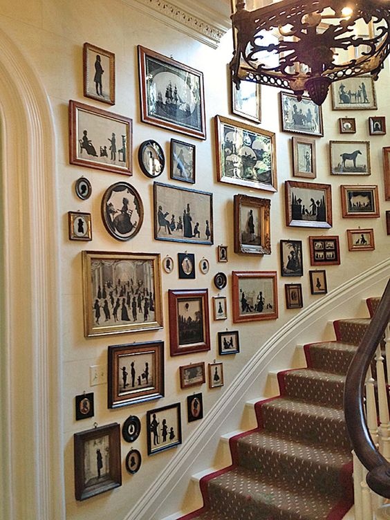 A vintage gallery wall with artwork and photos in different and chic frames that are gilded and not only fit the room perfectly