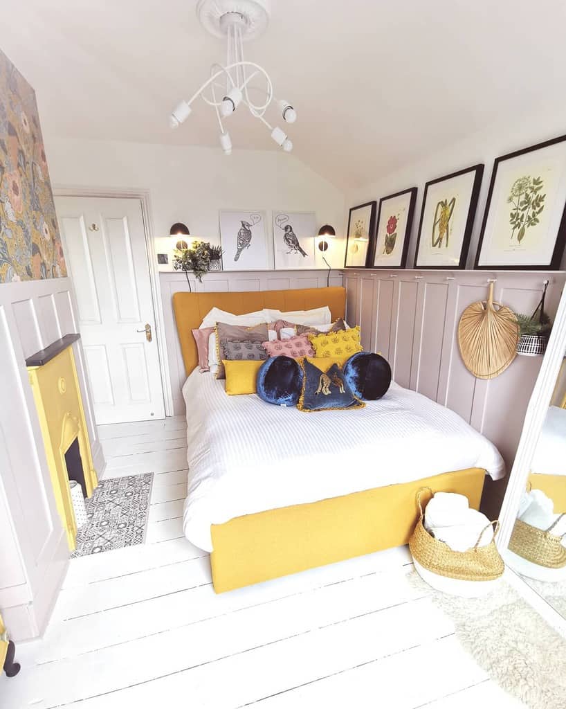 small bedroom, white wall paneling, yellow bed and fireplace 