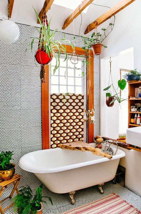 a bright bathroom with penny tiles, richly stained wood beams, a claw-foot tub, a floating vanity and a wooden bookcase, and plenty of potted plants