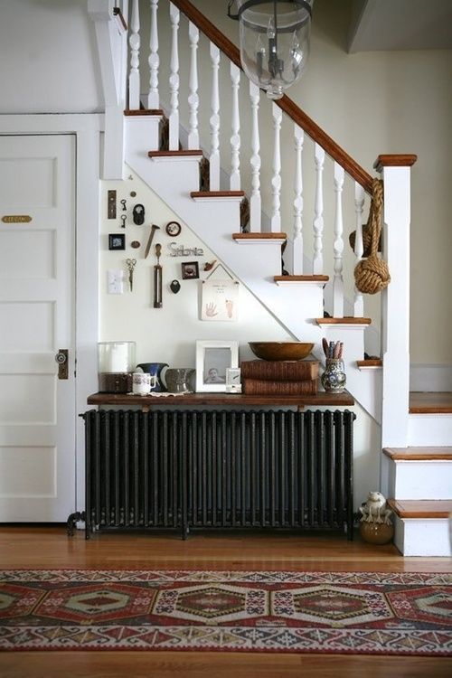 a black radiator with a stained shelf above it, with books, decorations and candles and a gallery wall for a vintage room