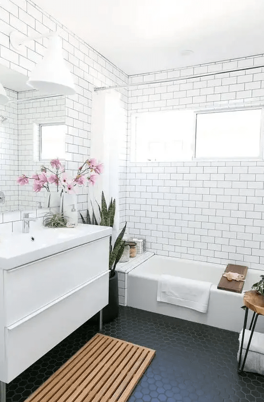 A bathroom with subway tiles, accented black grout and black hexagon tiles on the floor is on trend
