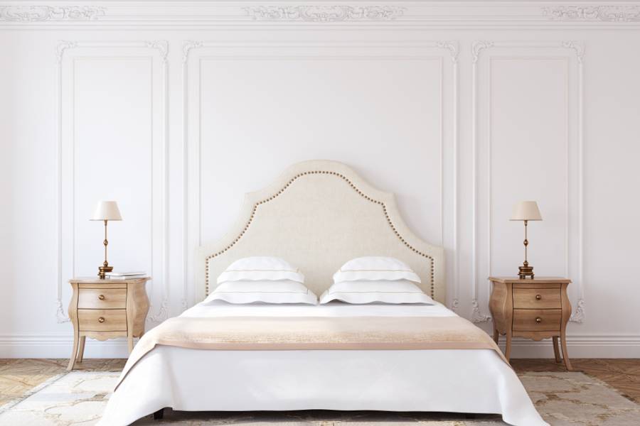 Large white bedroom wall, elegant wooden bedside tables with headboard 