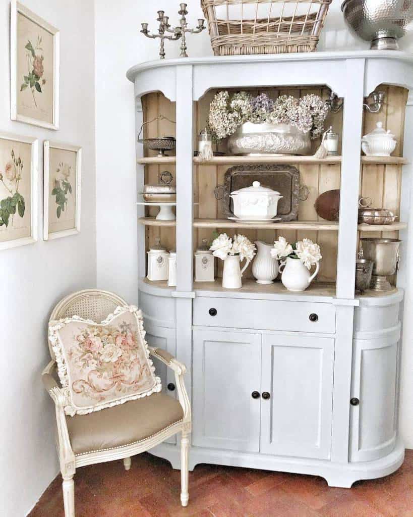 White cabinet with shelves accenting a wicker chair with floral cushions