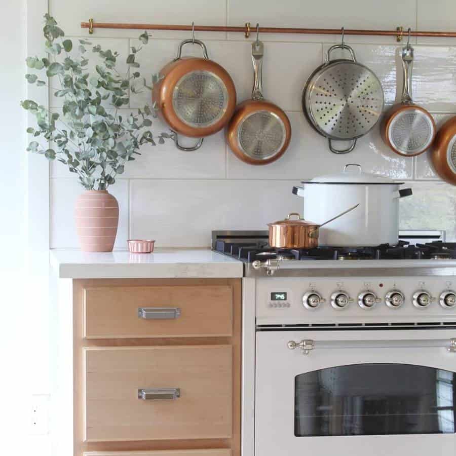small kitchen, white oven, hanging pots and pans, white tile wall plant