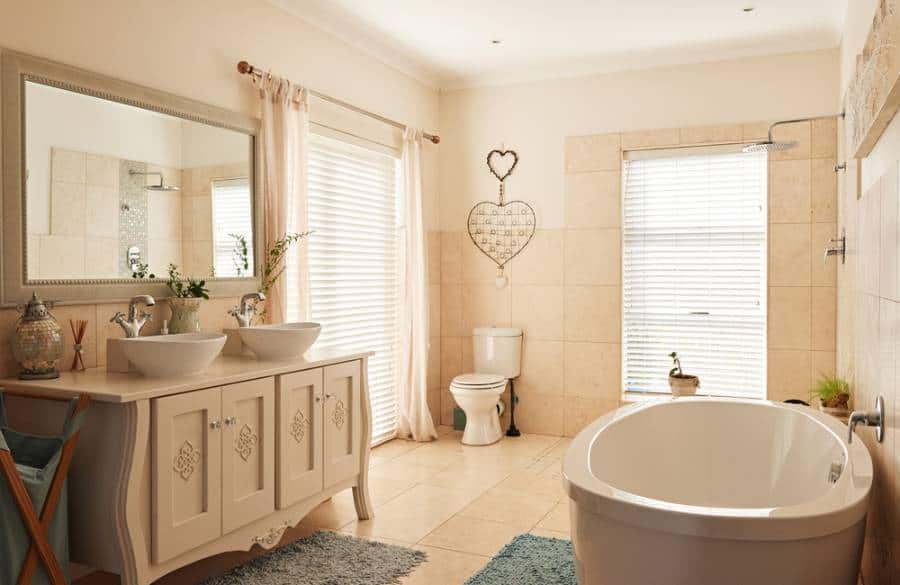 Beige country house bathroom, freestanding bathtub, large mirror, two vanities 