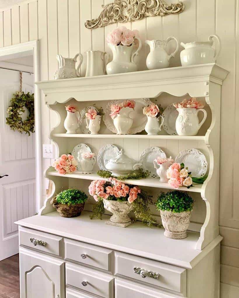 White vintage cupboard with cutlery and pink roses 