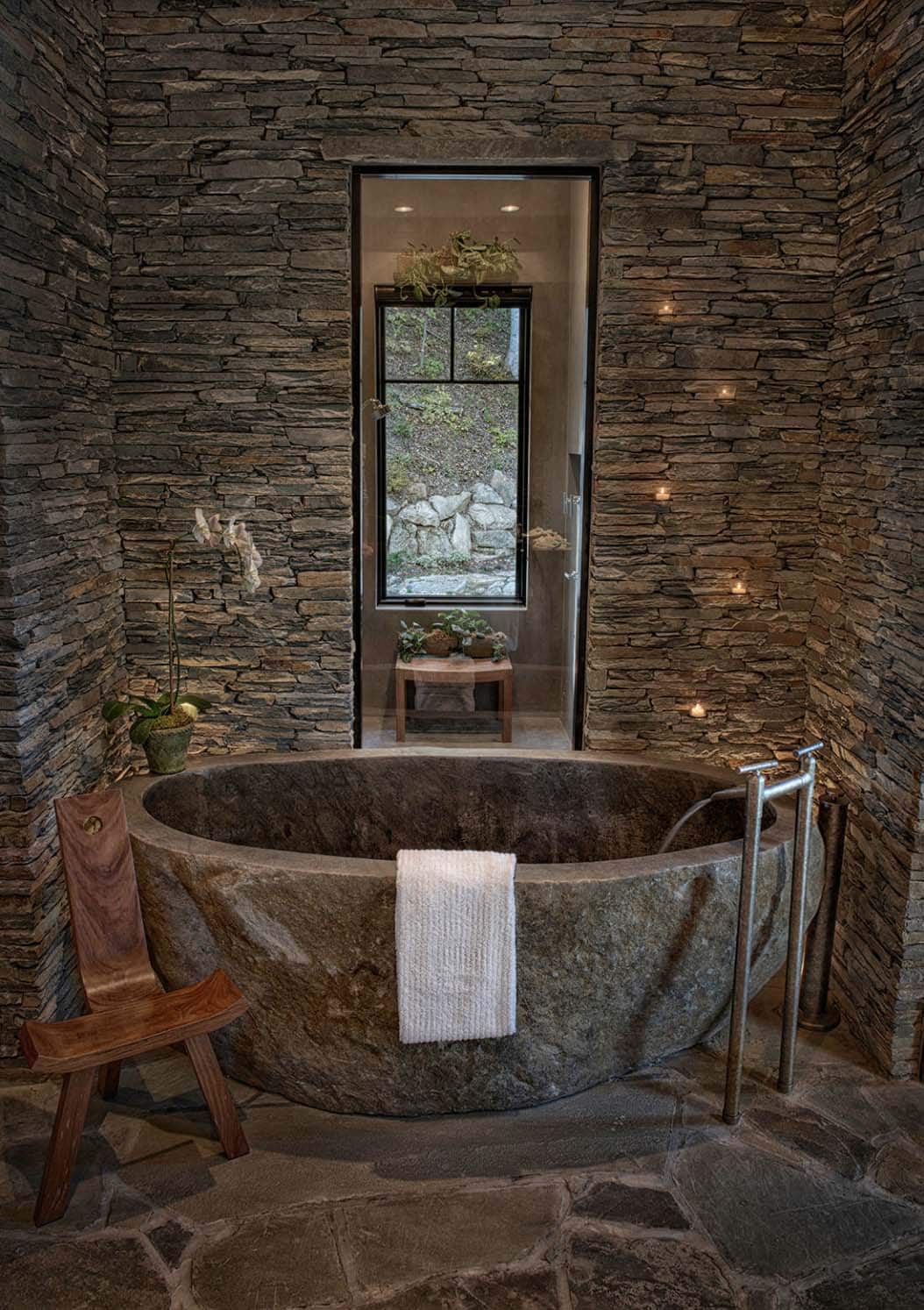 romantic rustic bathroom with stone tub and stone walls