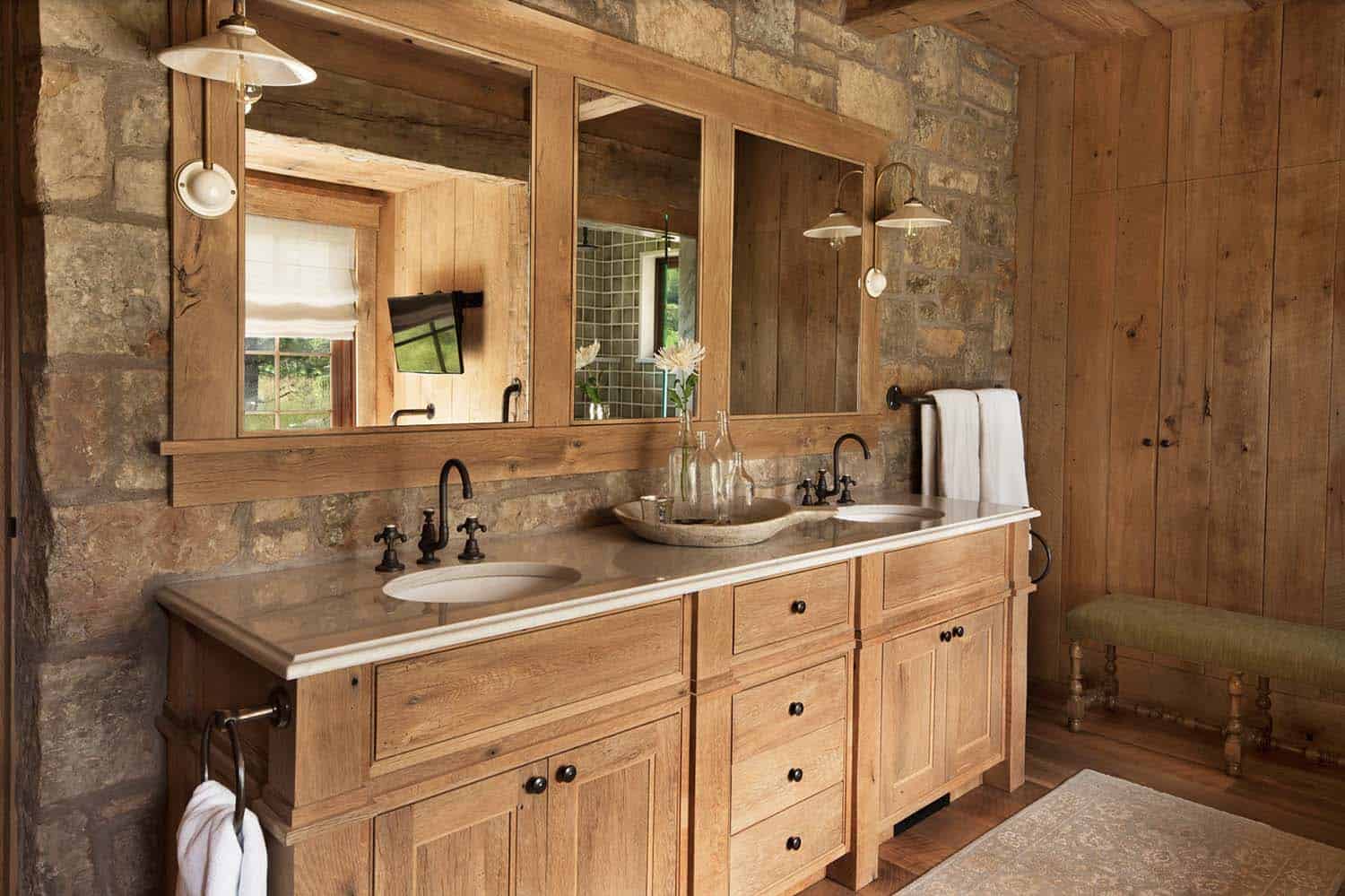 Rustic bathroom with double sinks and stone wall