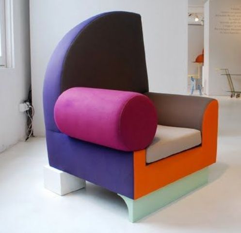 An armchair in a color block design with different armrests, a purple backrest, a gray seat, a fuchsia armrest and a pastel green base will make a statement