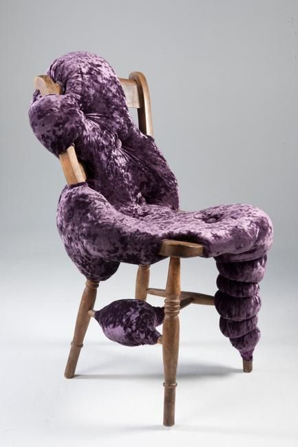 A stained vintage chair with purple upholstery, placed chaotically as if slime is spilling onto the floor
