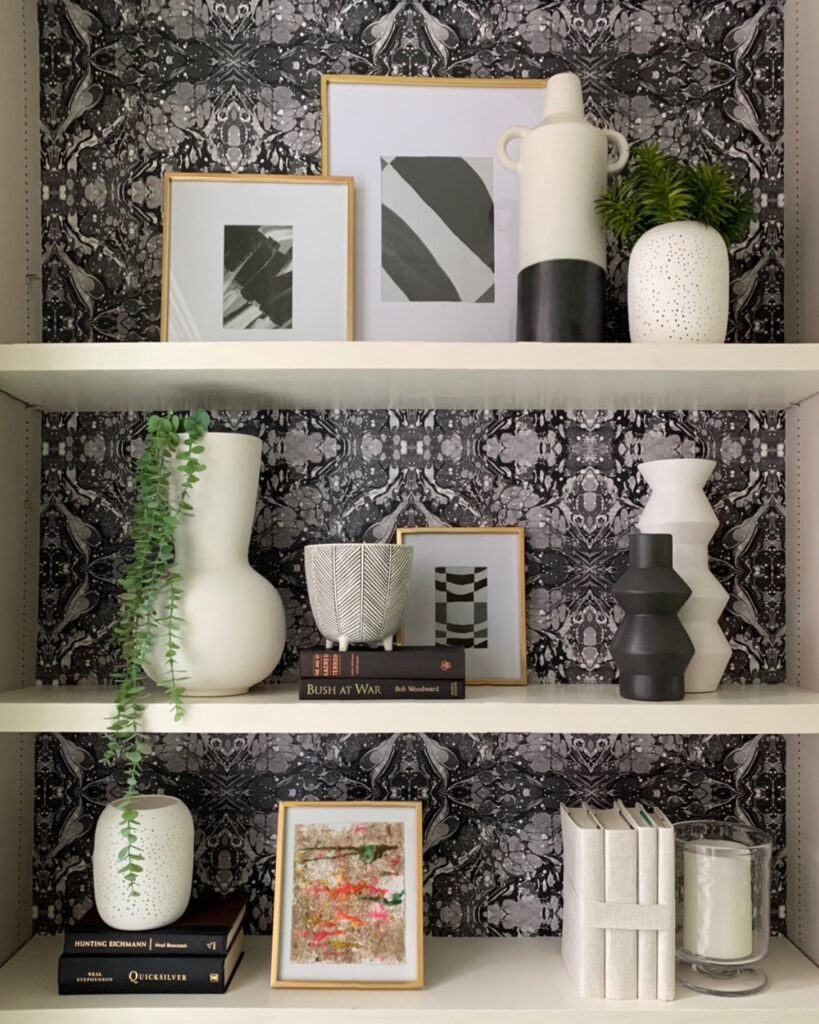 Neutral gray and white patterned wallpaper on white shelves with black and white decor