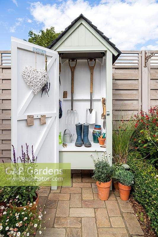 Mini wooden garden shed filled with garden tools | Outdoor garden .